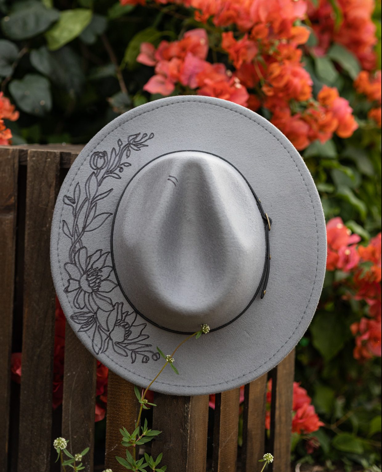 Newborn girl propped up in a blue bucket with pink and blue fabric and a knit layer. She is wearing a floral headband and is outside at Koreshan park in estero florida in front of a bridge. Outdoor newborn photographer fort myers Florida